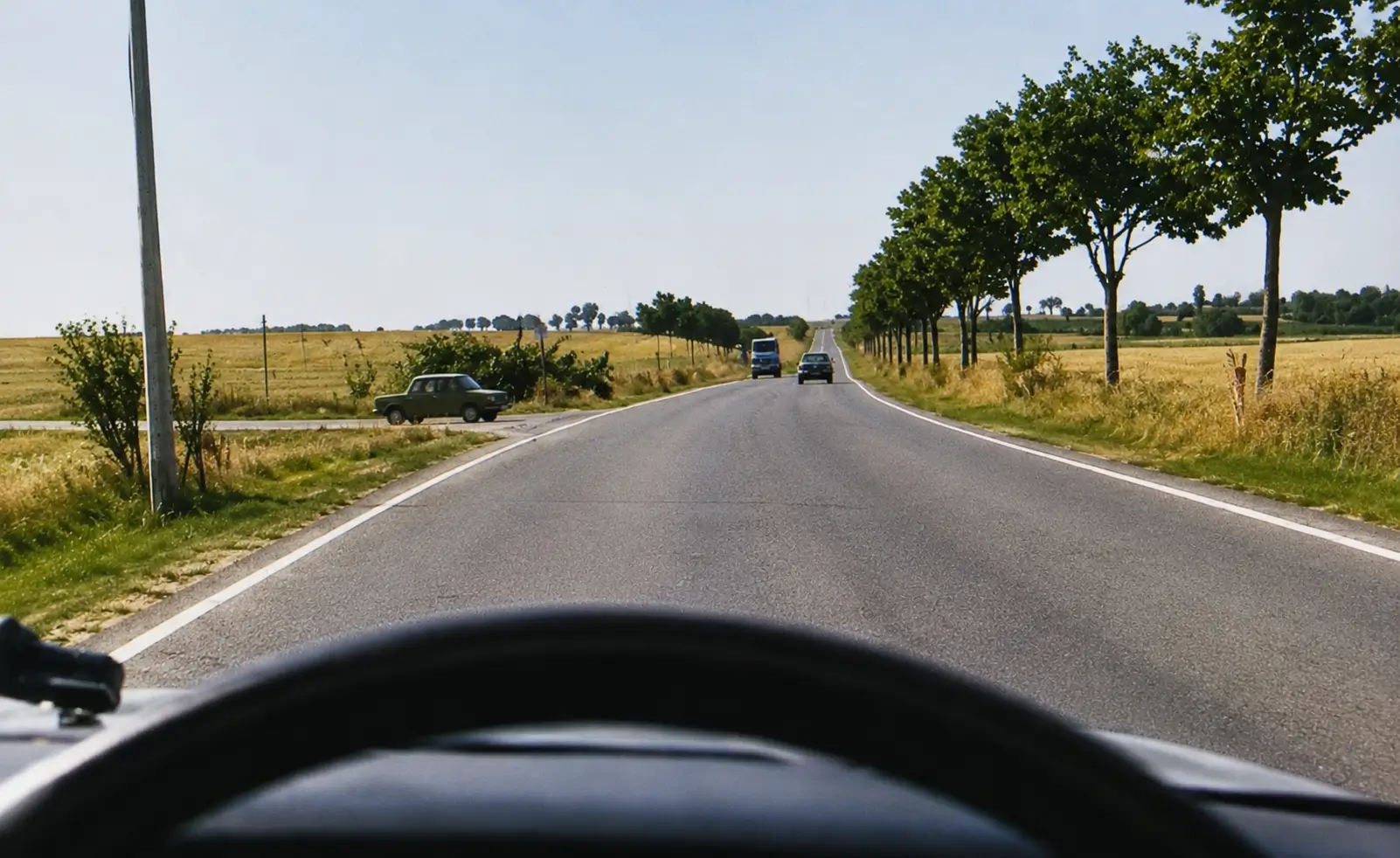 Driver's view from a main road looking at a car entering from a farm track on the left